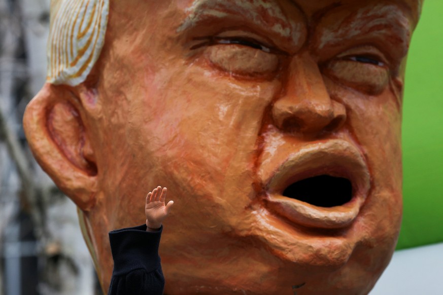 A protestor waves to supporters with a miniature hand while wearing an oversized replica of the head of U.S. President Donald Trump outside of the U.S. District Court during a rally in support of Dani ...