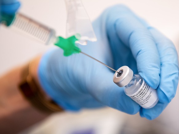 ARCHIV - Eine Klinik-Mitarbeiterin zieht den Covid-19 Impfstoff von Biontech/Pfizer f�r eine Impfung auf eine Spritze. Ab sofort k�nnen mehr Menschen mit dem Impfstoff aus einer Ampulle der Hersteller ...