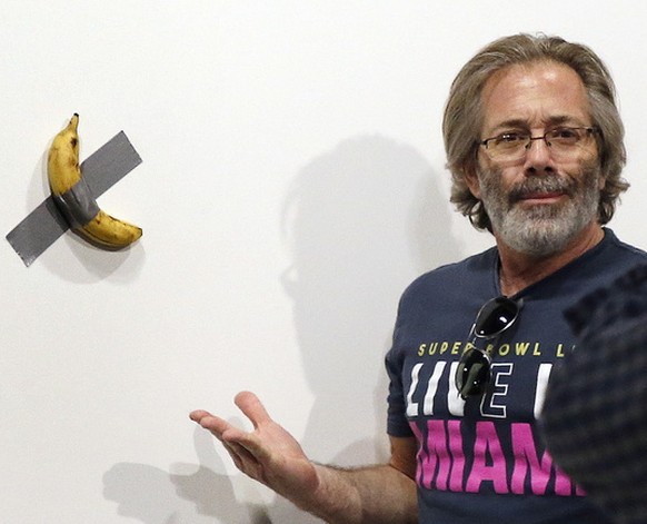 epa08047505 Art patrons take a picture with Italian artist Maurizio Cattelan piece&#039;s &#039;Comedian&#039; (a banana duct taped to the wall) during Art Basel in Miami, Florida, USA, 05 December 20 ...