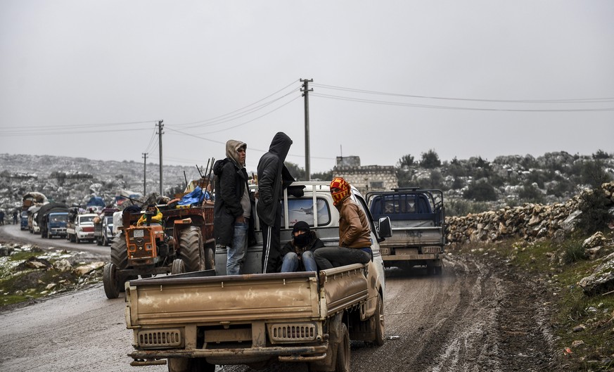 Syrian civilians flee from Idlib in rain toward the north to find safety inside Syria near the border with Turkey, Thursday, Feb. 13, 2020. Syrian troops are waging an offensive in the last rebel stro ...