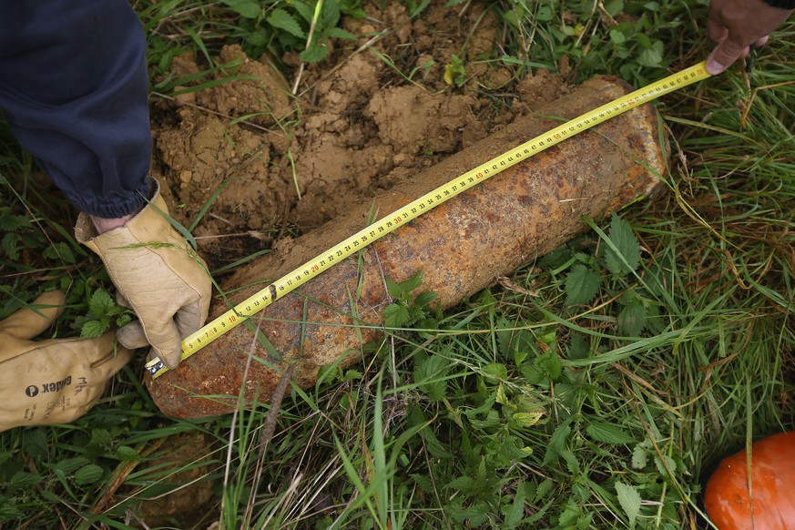 VERDUN, FRANCE - AUGUST 26: Mine-clearing specialists Guy Momper and Raoul Weber measure an unexploded German 155mm artillery shell from World War I found by a local farmer in a field at Champneuville ...