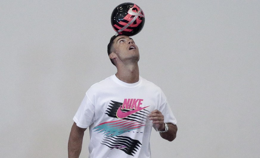 epaselect epa07694027 Portuguese soccer player Cristiano Ronaldo balances a ball on his head during a public appearance by the player at Yumin Primary School in Singapore, 04 July 2019. Ronaldo is vis ...