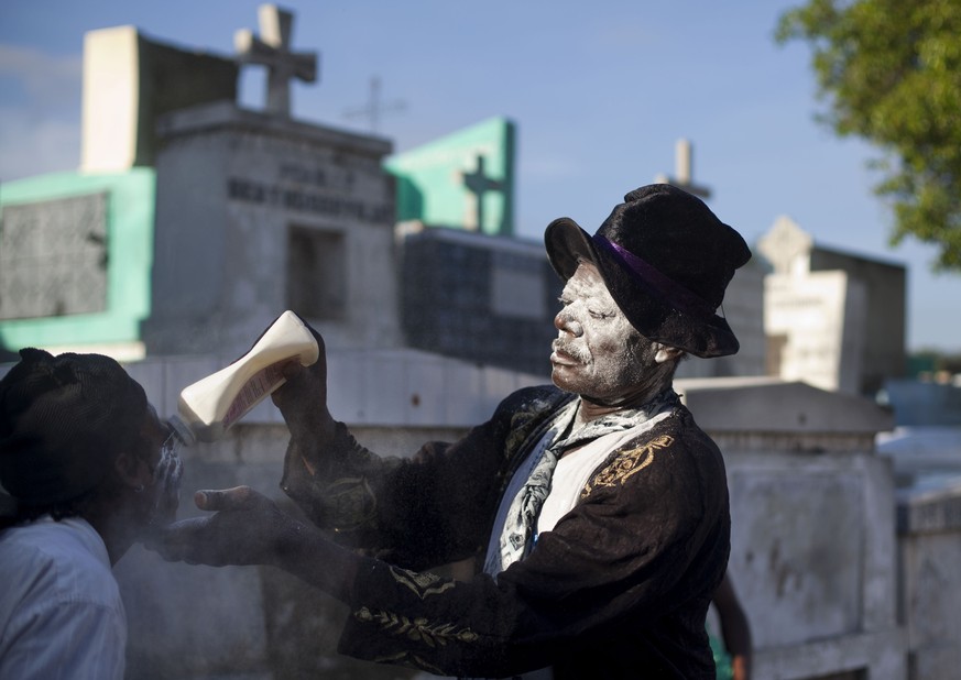 Charles Benest, a voodoo priest puts powder to the face of a believer during a Voodoo ritual that pays tribute to Baron Samdi and the Gede family of spirits during Day of the Dead celebrations at the  ...