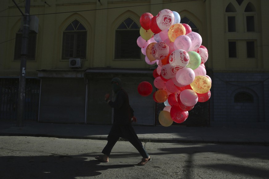 A man walks with colored balloons for sale during the first day of Eid al-Fitr during a lockdown aimed at curbing the spread of the coronavirus in Kabul, Afghanistan, Sunday, May 24, 2020. The Taliban ...
