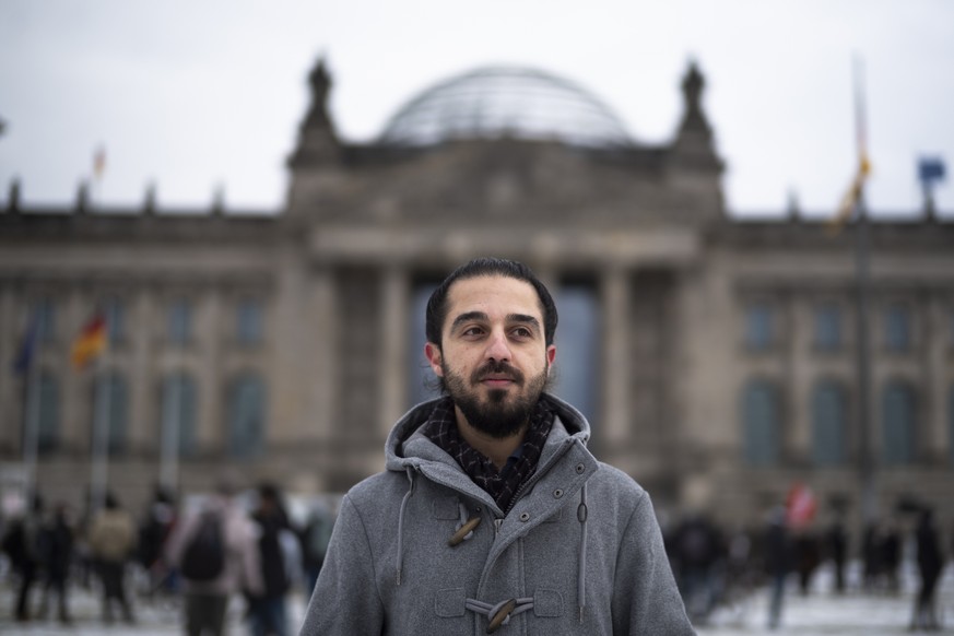 FILE - In this Saturday, Feb. 6, 2021 file photo Tareq Alaows, who is running to become a lawmaker at the German parliament Bundestag poses in front of the Reichstag building in Berlin, Germany. Tareq ...