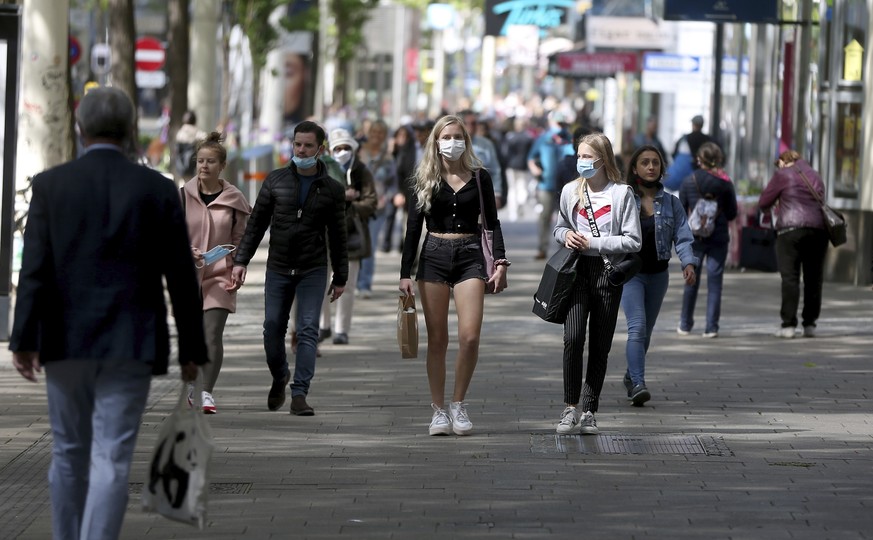 People, many wearing a protective masks walk in a street in Vienna, Austria, Saturday, May 2, 2020 after certain shops and businesses were allowed to reopen. The Austrian government has moved to restr ...