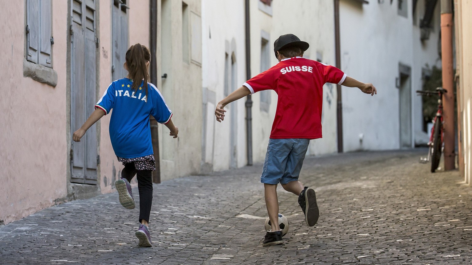 Das Fussballfieber ist nun auch in der Schweiz angekommen: Zwei Kinder mit einem italienischen und einem Schweizer Fussballtrikot spielen am Freitag, 3. Juni 2016, in den Gassen der Altstadt in Zug Fu ...