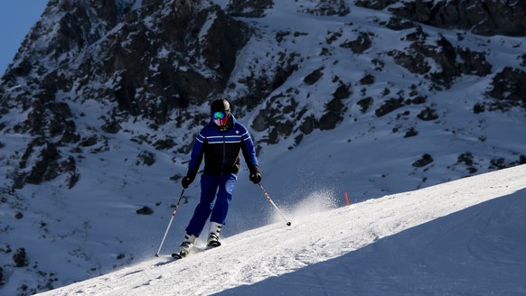 epa08785753 A skier wearing face mask ski down the slope on the opening day of the Verbier ski area in the Swiss Alps during the coronavirus disease (COVID-19) outbreak, in Verbier, Switzerland, 30 Oc ...