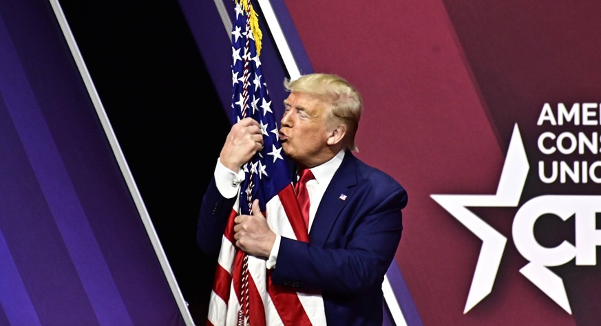 February 29, 2020, National Harbor, Maryland, USA: United States President DONALD J. TRUMP embraces the American Flag after speaking at the Conservative Political Action Conference CPAC at the Gaylord ...
