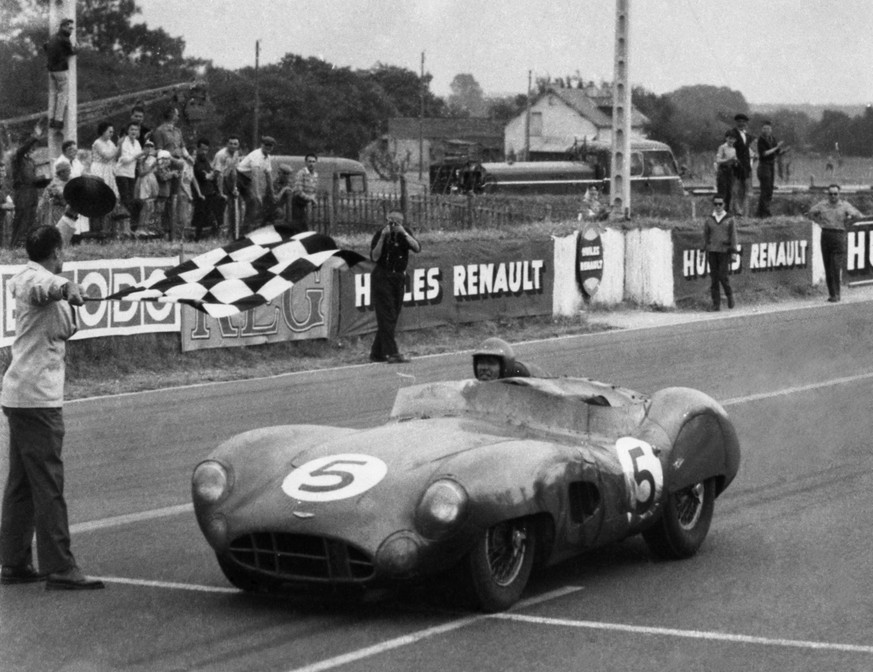 An official doff his hat as he waves the chequered flag as Carroll Shelby of Dallas, Texas crosses the finish line driving an Aston Martin to win the 24 hour race in Le Mans, France on June 21, 1959.  ...
