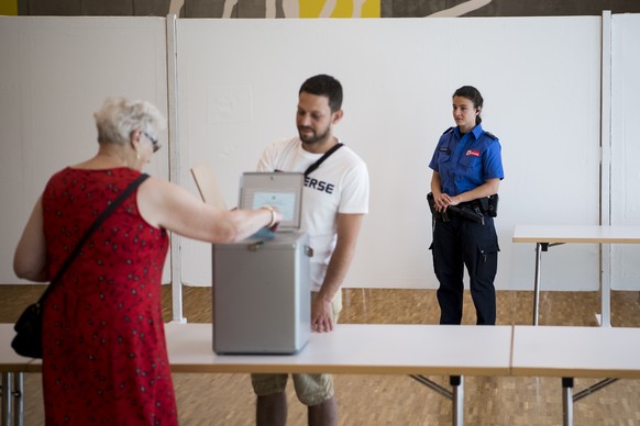 Une policiere bernoise observe le bon deroulement du scrutin devant l&#039;urne du bureau de vote installe a la Societ&#039;halle ce dimanche 18 juin 2017 a Moutier. Le 18 juin, les citoyens de Moutie ...