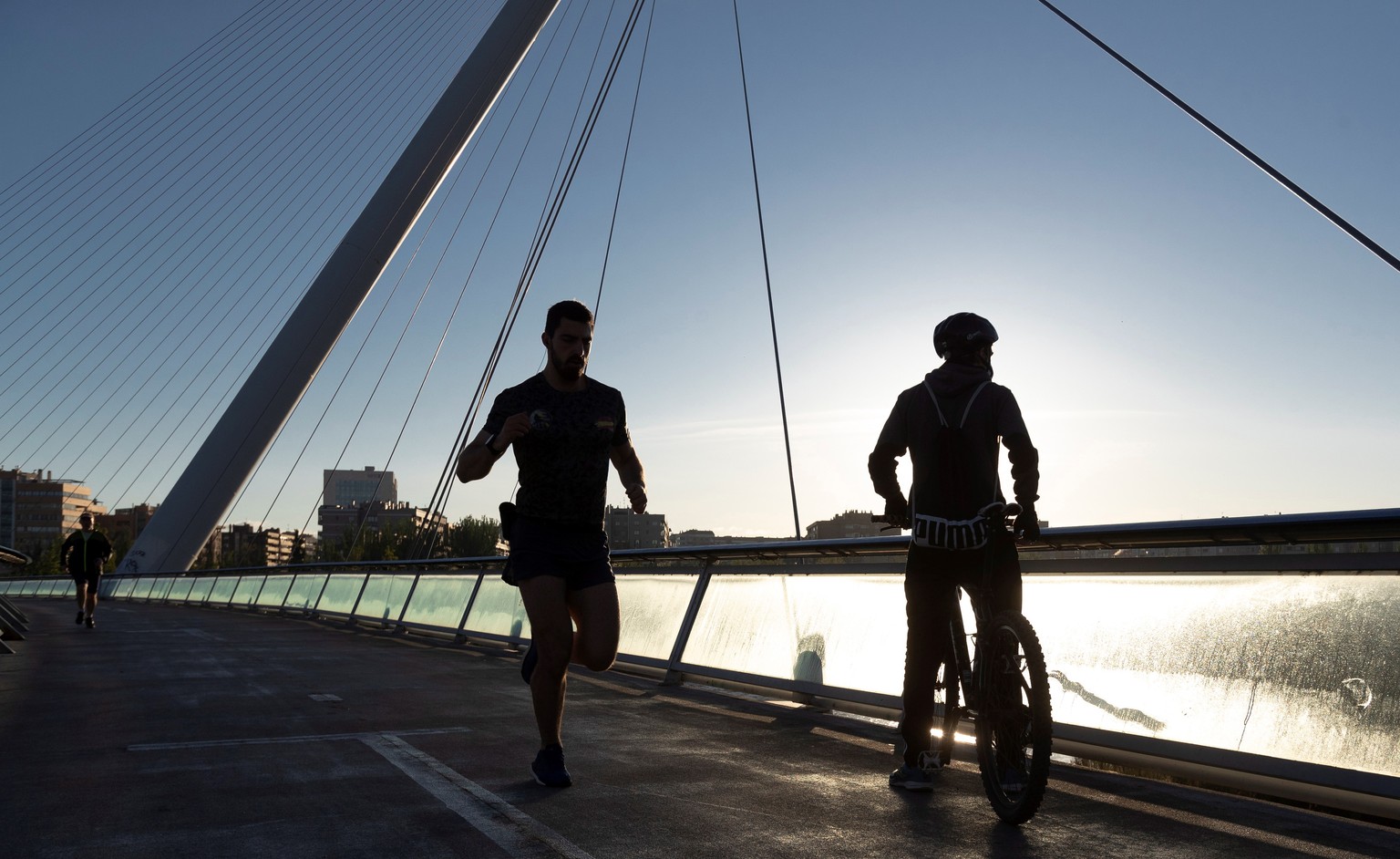 epaselect epa08397113 A runner and a cyclist go for an early-morning run and bike ride in Zaragoza, northeastern Spain, 02 May 2020. Starting on 02 May, Spain has started loosening some of the strict  ...