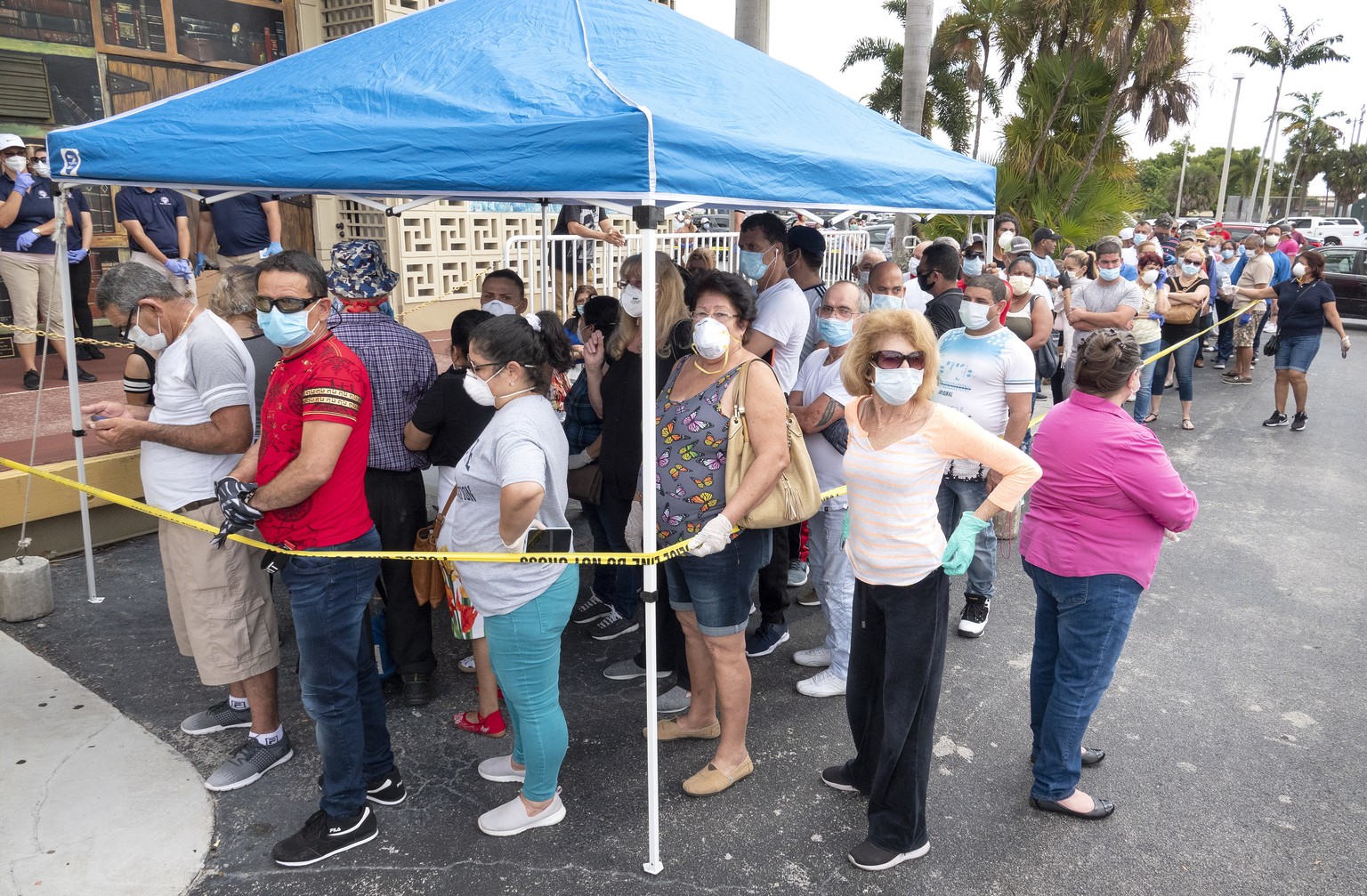 epa08348692 People queue to receive the printed Unemployment Benefits applications in the parking lot of Kennedy Library in Hialeah, Florida, USA, 07 April 2020. Hundreds of residents lined up hours b ...