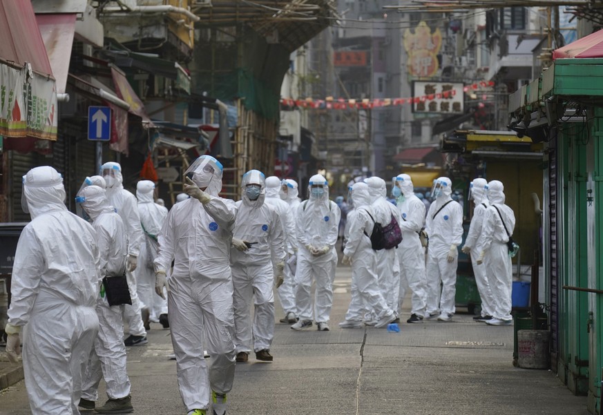 Government investigators wearing protective suits, gather in the Yau Ma Tei area, in Hong Kong, Saturday, Jan. 23, 2021. Thousands of Hong Kong residents were locked down Saturday in an unprecedented  ...