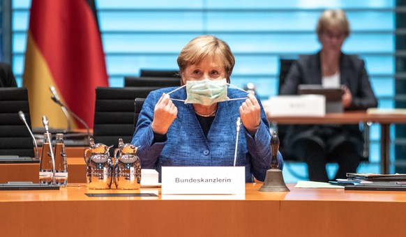 epa08725858 German chancellor Angela Merkel adjusts her face mask during a Cabinet Meeting in Berlin, Germany, 07 October 2020. EPA/ANDREAS GORA / POOL Pool Photo