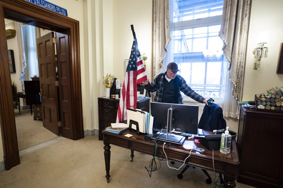 epa08926303 Richard Bigo Barnett, a supporter of US President Donald J. Trump and his baseless claims of voter fraud, takes a seat in the office of Speaker of the House Nancy Pelosi after breaching Ca ...