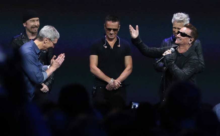 epa04393170 Apple CEO Tim Cook (L) talks with lead singer Bono (R) and members of the Irish group U2 during Apple&#039;s launch event at the Flint Center for the Performing Arts in Cupertino, Californ ...
