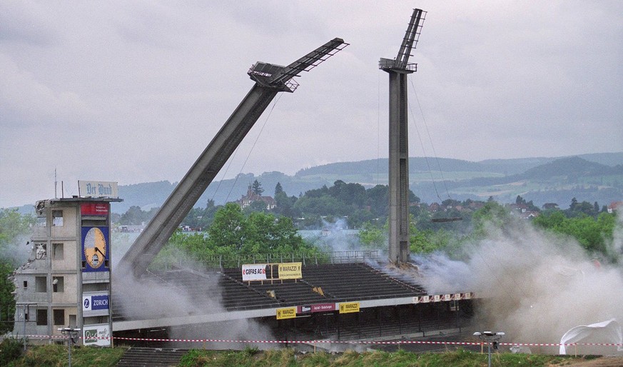 Smoke raises from the Wankdorf-Stadium in Bern, Switzerland, on Friday, August 3, 2001, after the four 50 meters high flood light masts and the roof of the main stand have been detonated to make place ...