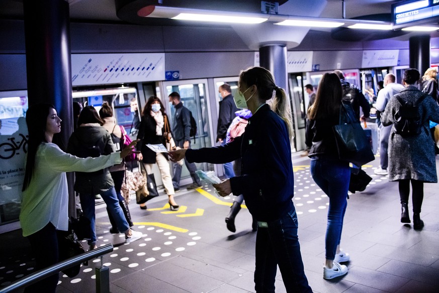 epa08414950 A commuter takes a protective face mask freely distributed by an employee of Lausanne&#039;s public transport at the metro m2 station and train CFF/SBB station during the spread of the pan ...