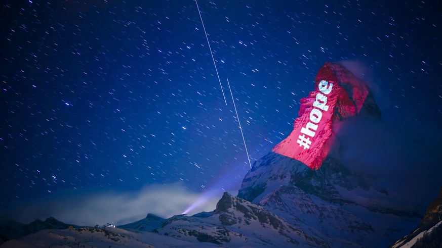 epa08325844 The iconic Matterhorn mountain is illuminated by Swiss light artist Gerry Hofstetter aiming to send messages of hope, support and solidarity to the ones sufferings from the global coronavi ...