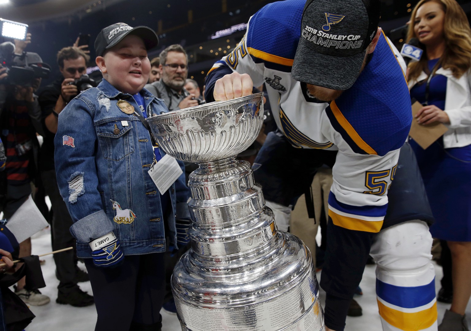 St. Louis Blues fan Laila Anderson, left, watches Colton Parayko lift the Stanley Cup while the team celebrated on the ice after the Blues defeated the Boston Bruins in Game 7 of the NHL Stanley Cup F ...
