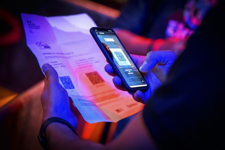A security staff of the MAD (Moulin a Danse) night club scans the QR code of a COVID-19 certificate allowing entry in newly reopened nightclubs in Lausanne, Switzerland, late Friday, June 25, 2021. (K ...