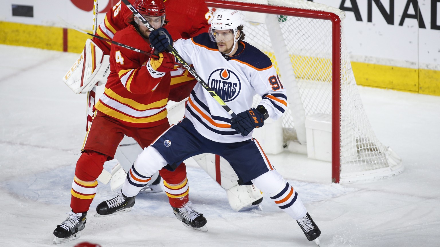 Edmonton Oilers&#039; Gaetan Haas, right, and Calgary Flames&#039; Rasmus Andersson tangle in front of goalie Jacob Markstrom during the first period of their NHL hockey game in Calgary, Monday, March ...