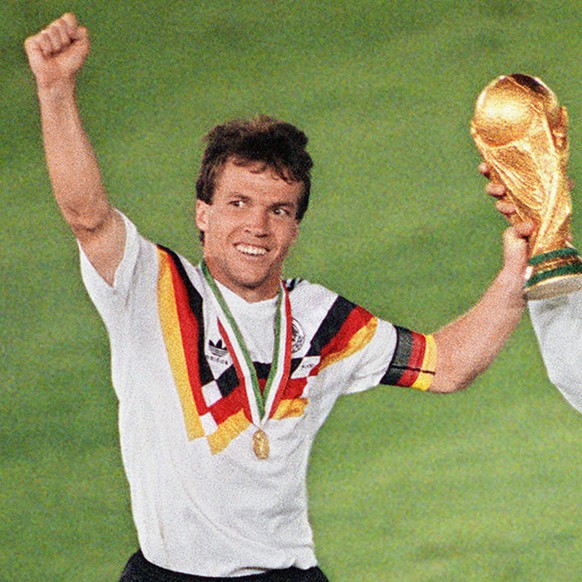 West German midfielder Lothar Matthaeus (L) and forward Pierre Littbarski celebrate with the World Cup trophy after their team beat the defending champions Argentina 1-0 on a penalty kick by defender  ...