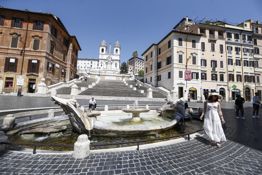 People stand next to the 17th century Barcaccia fountain, in front of the Spanish Steps, in Rome, Thursday, July 23, 2020. Like most tourists sites in Rome, the Spanish steps would usually be crowded  ...