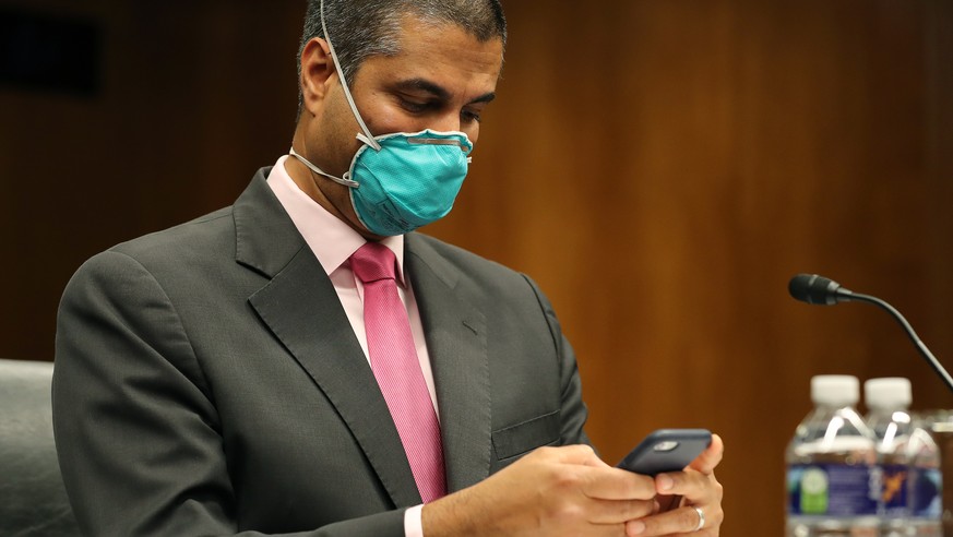 epa08488488 FCC Chairman, Ajit Pai, looks at his electronic device before testifying before a Senate Appropriations Subcommittee hearing on Capitol Hill in Washington, DC, USA, 16 June 2020. The heari ...