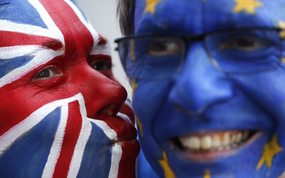FILE - In this Thursday, March 21, 2019 file photo, activists pose with their faces painted in the EU and Union Flag colors during an anti-Brexit campaign stunt outside of an EU summit in Brussels.Bri ...