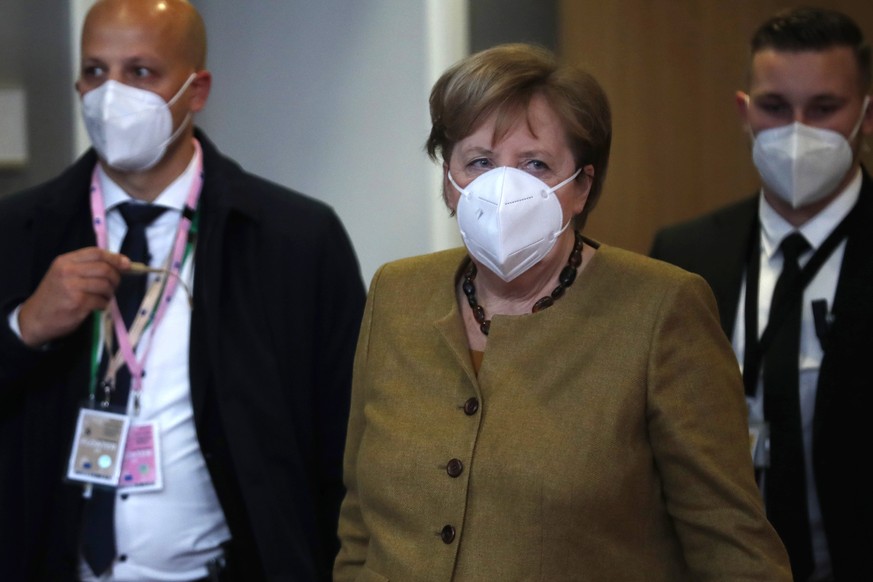 German Chancellor Angela Merkel, center, leaves at the end of an EU summit in Brussels, Friday, Dec. 11, 2020. European Union leaders have reached a hard-fought deal to cut the bloc&#039;s greenhouse  ...