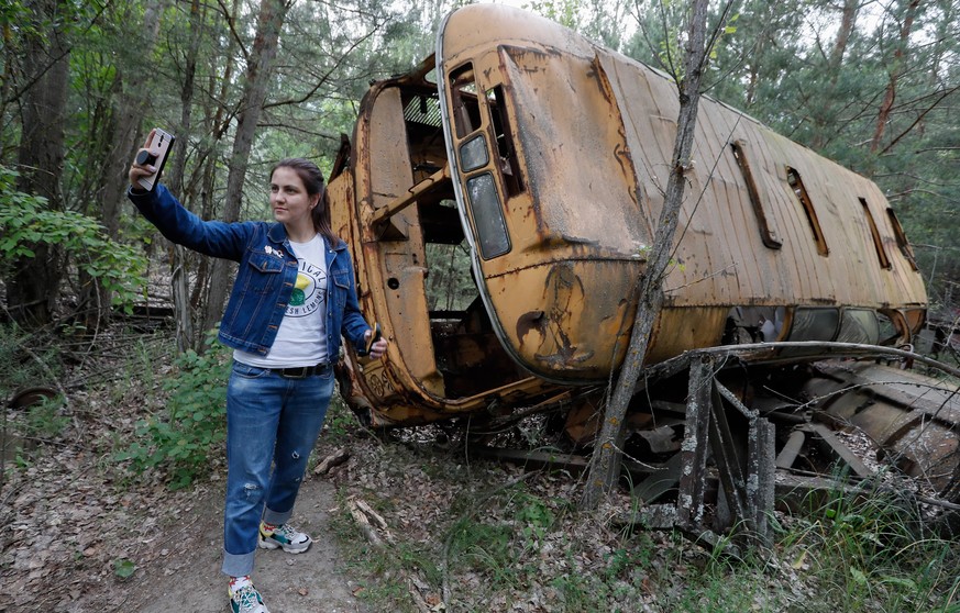 epaselect epa07633614 A visitor takes a selfie with an abandoned bus during a tour in Chernobyl, Ukraine, 07 June 2019. The miniseries Chernobyl (2019) made by HBO depicts the explosion`s aftermath, t ...