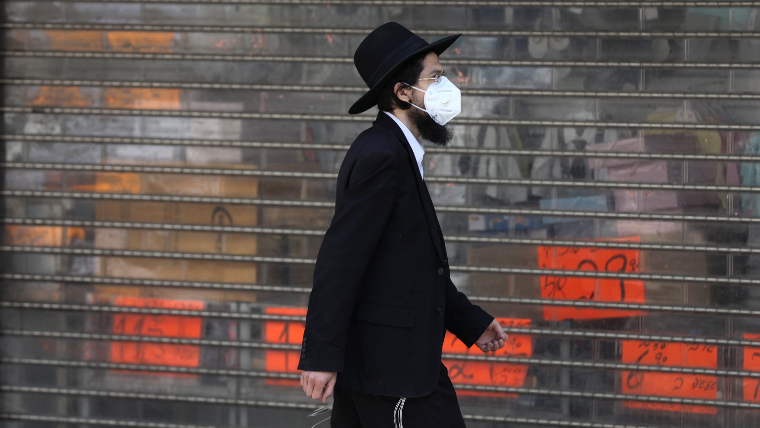 epa08340685 Ultra Orthodox Jewish man wearing a protective face mask passes an empty main street in the city of Bnei Brak , Israel, 03 April 2020. The media report that Israeli Police have closed the  ...