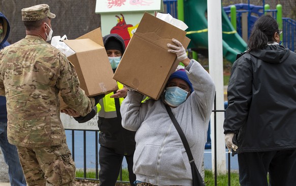epa08373881 Residents carry away boxes of food as members of the Forward Support Company 101st Engineering Battalion Massachusetts Army National Guard distribute food at a temporary food pantry locati ...