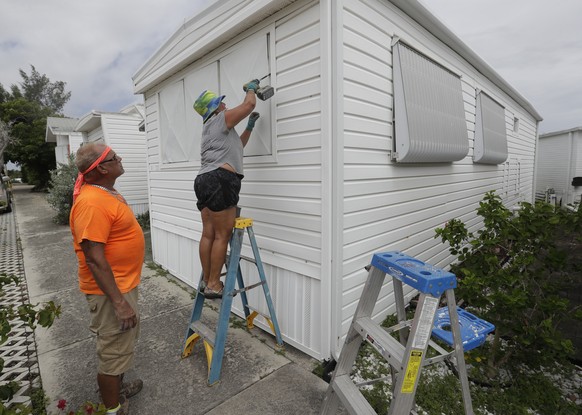 Chris Nagiewicz, left, watches as his wife Mary screws in a hurricane panel, Saturday, Aug. 1, 2020, on a trailer home in Briny Breezes, Fla. Hurricane Isaias is headed toward the Florida coast, where ...