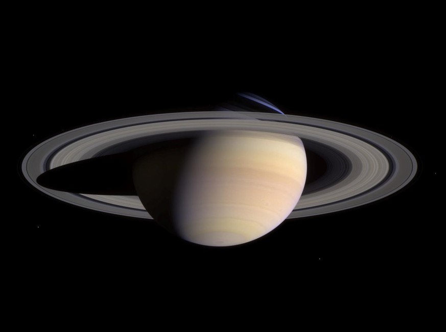 This composite of two images, taken by the Cassini spacecraft May 7, 2004 and released Tuesday June 29, 2004, shows a wide view of Saturn. The white dots in the image are some of Saturn&#039;s moons.  ...
