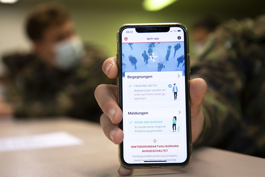 Soldier of the Swiss army wearing protective face mask looking at a smartphone with the app using Decentralized Privacy-Preserving Proximity Tracing (DP-3T) during a test, with 100 soldiers, during th ...