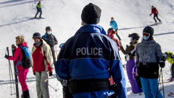 Un policier municipal de Bagnes controle des skieurs portant des masques de protection qui terminent une piste de ski sur le domaine skiable valaisan pendant la crise du Coronavirus (Covid-19) le same ...