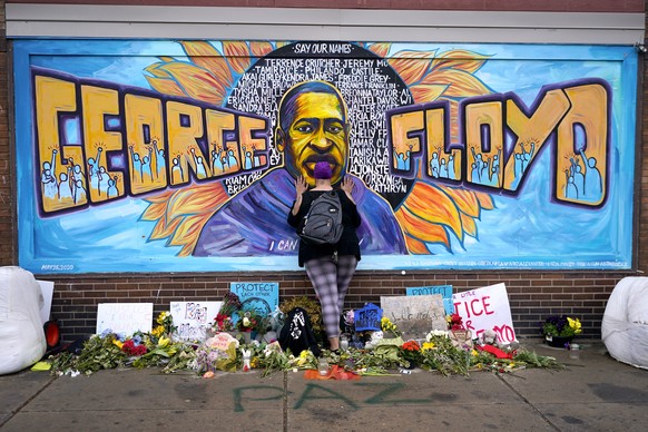 Damarra Atkins pays respect to George Floyd at a mural at George Floyd Square, Friday, April 23, 2021, in Minneapolis. (AP Photo/Julio Cortez)