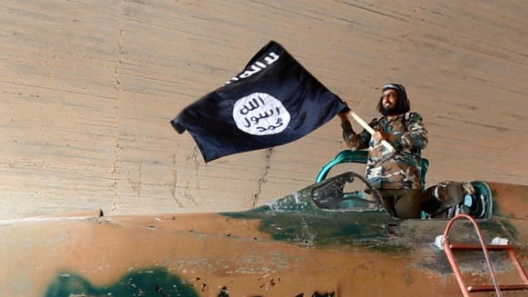 Ein Kämpfer der Terrorgruppe Islamischer Staat (IS) mit einer Flagge. (Symbolbild)