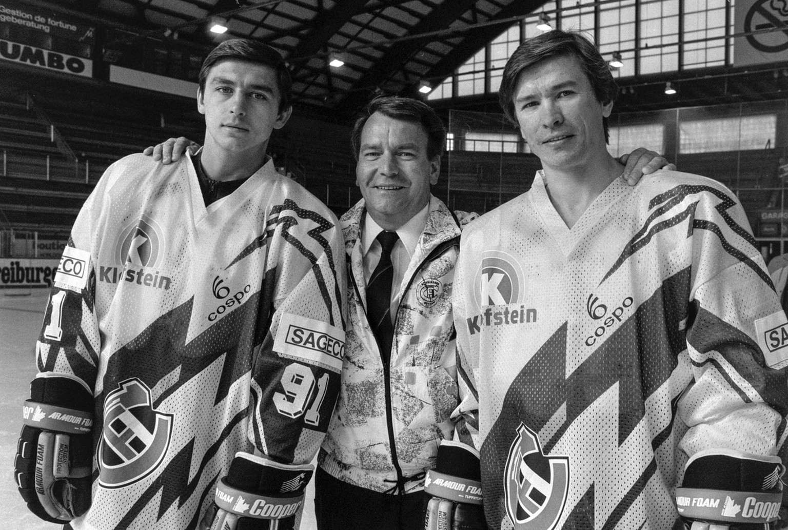 Jean Martinet, Mitte, Praesident des Eishockeyclubs HC Fribourg-Gotteron, mit den zwei Russen im Club Slawa Bykow, rechts, und Andrei Chomutow, links, aufgenommen im Oktober 1990. (KEYSTONE/Str)