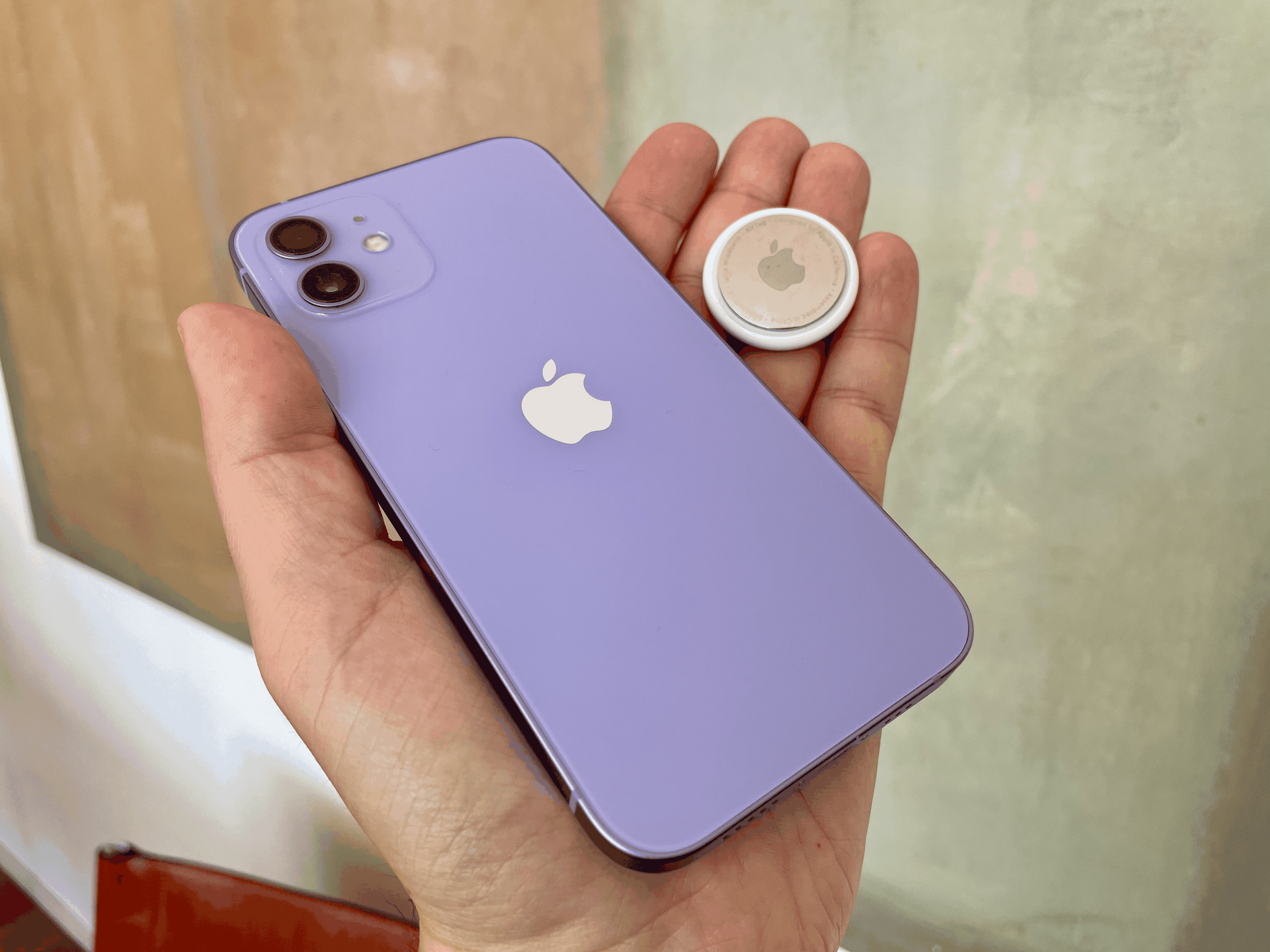 Das iPhone 12 in Violett, zusammen mit einem AirTag von Apple.