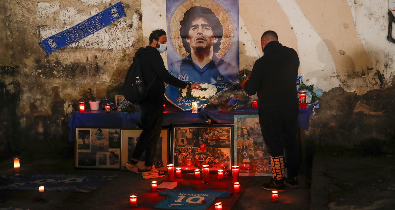 People gather and light candles to honor soccer legend Diego Maradona, at the popular &quot;Quartieri Spagnoli&quot; neighborhood, in Naples, Thursday, Nov. 26, 2020. Maradona died on Wednesday at the ...