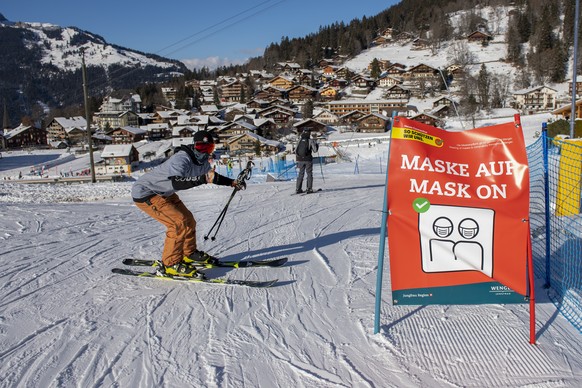 Skifahrer mit Schutzmaske im Dorf Wengen, aufgenommen am Freitag, 8. Januar 2021, im Skigebiet Grindelwald - Wengen. Die Berner Skigebiete bleiben trotz Coronavirus geoeffnet, mit reduzierter Transpor ...