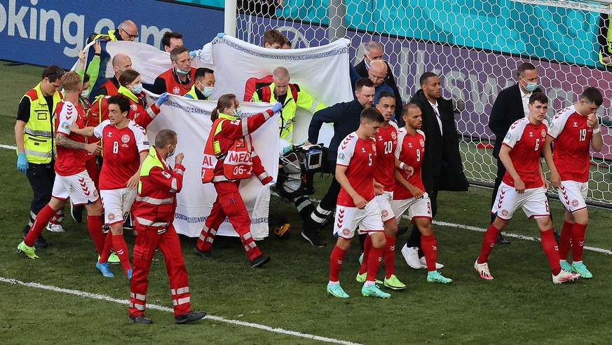 epa09265532 Players of Denmark escort their teammate Christian Eriksen as he is stretchered off the pitch after receiving medical assistanceduring the UEFA EURO 2020 group B preliminary round soccer m ...