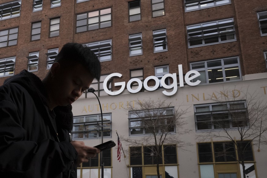 FILE - In this Dec. 17, 2018, file photo a man using a mobile phone walks past Google offices in New York. Australia���s laws forcing Google and Facebook to pay for news are ready to take effect, thou ...