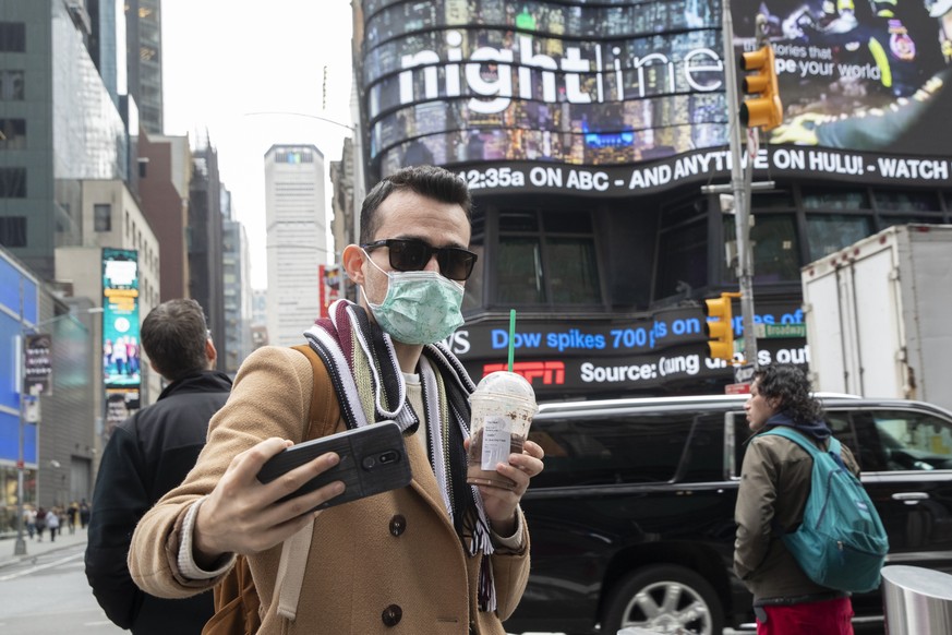 Justin Dalipi, of Albania, wears a mask as a precaution against the Corona virus during the final days of his visit to New York, as he takes a selfie in New York&#039;s Times Square, Tuesday, March 10 ...