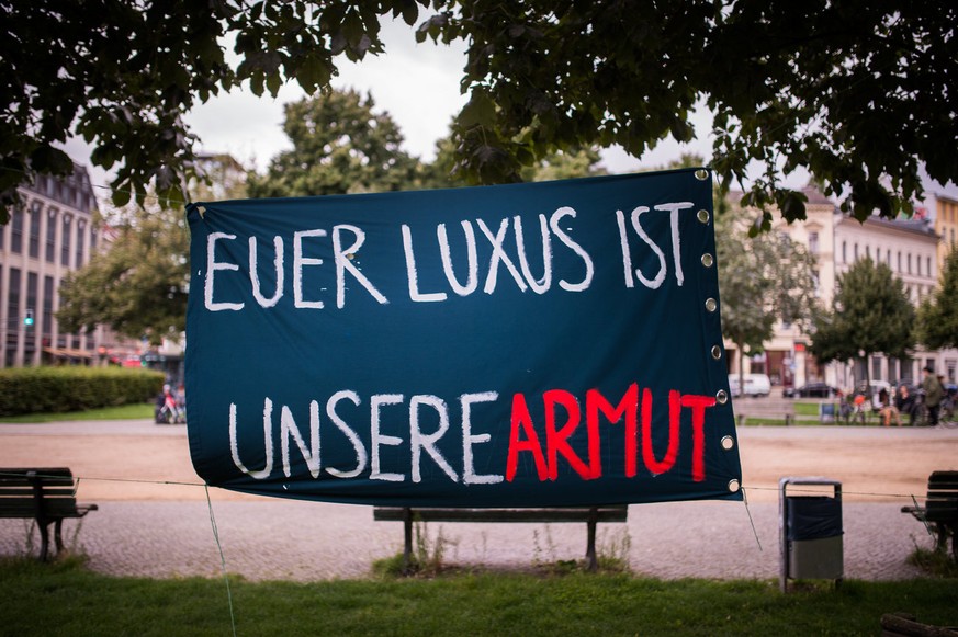 ARCHIV - 21.08.2017, Berlin: Vor einem Luxus-Hotel hängt ein Plakat mit der Aufschrift «Euer Luxus ist unsere Armut». (zu dpa «Studie: Wohlstand in Deutschland liegt nur auf Niveau der Neunziger» vom  ...