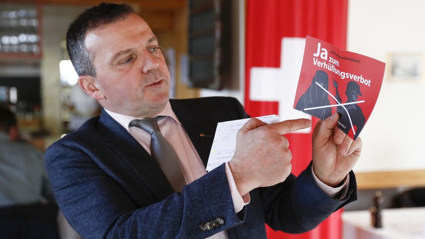 FILE - In this Feb. 12, 2017 file photo National Councillor Walter Wobmann displays a leaflet reading &quot;Yes to the ban on veiling&#039;&#039; at the reunion of the Swiss People&#039;s Party SVP in ...